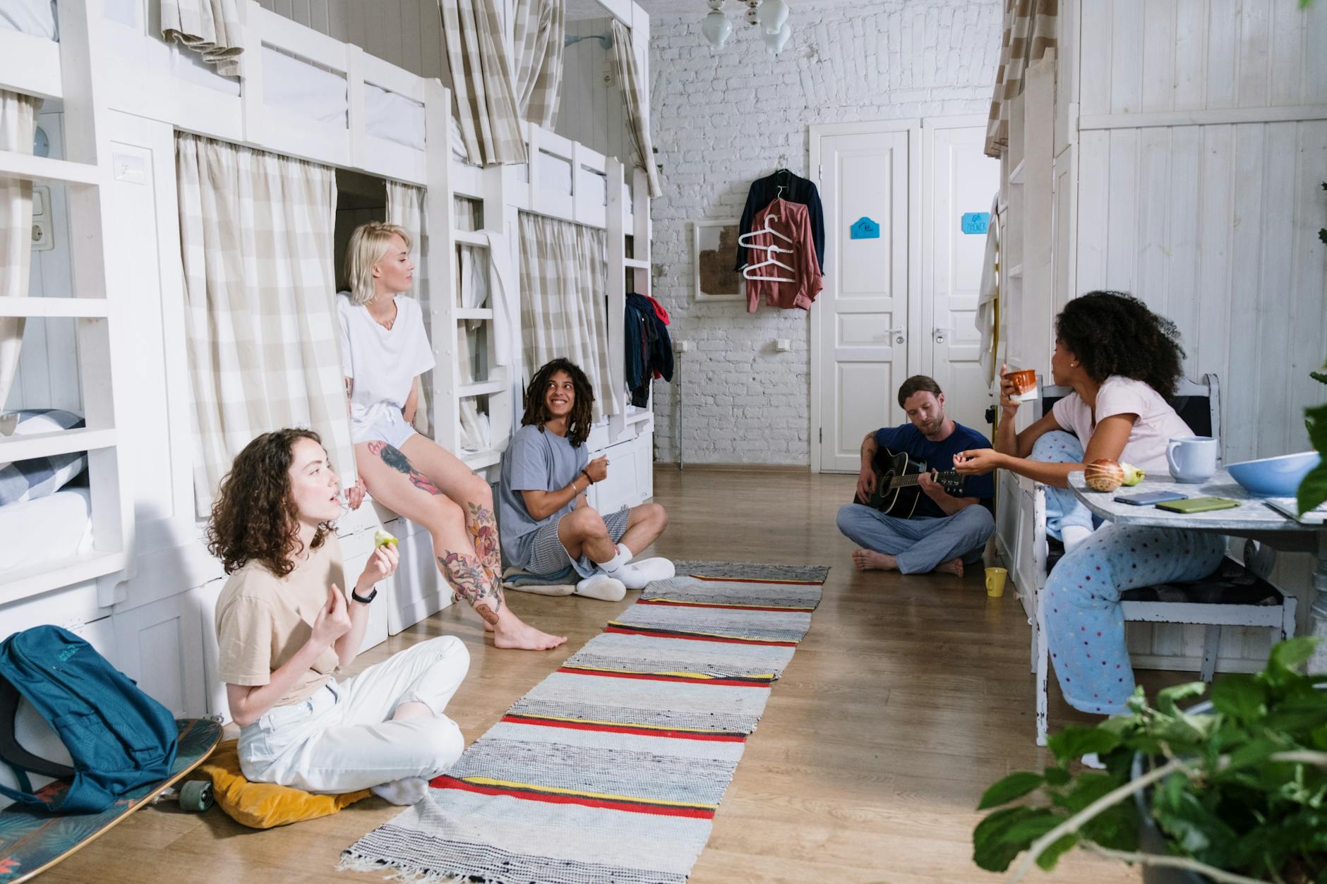 Diverse group of friends enjoying leisure time in a shared dorm with bunk beds