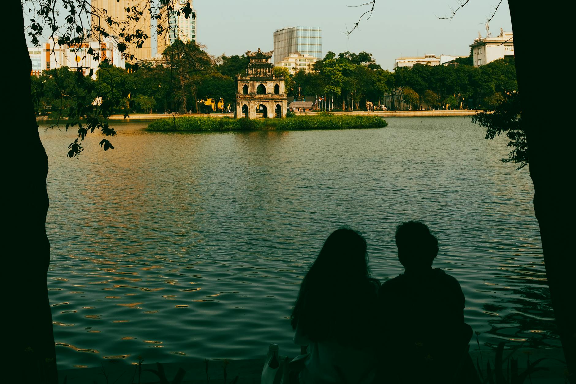 Silhouette of a couple enjoying a serene view of Hoan Kiem Lake with Turtle Tower