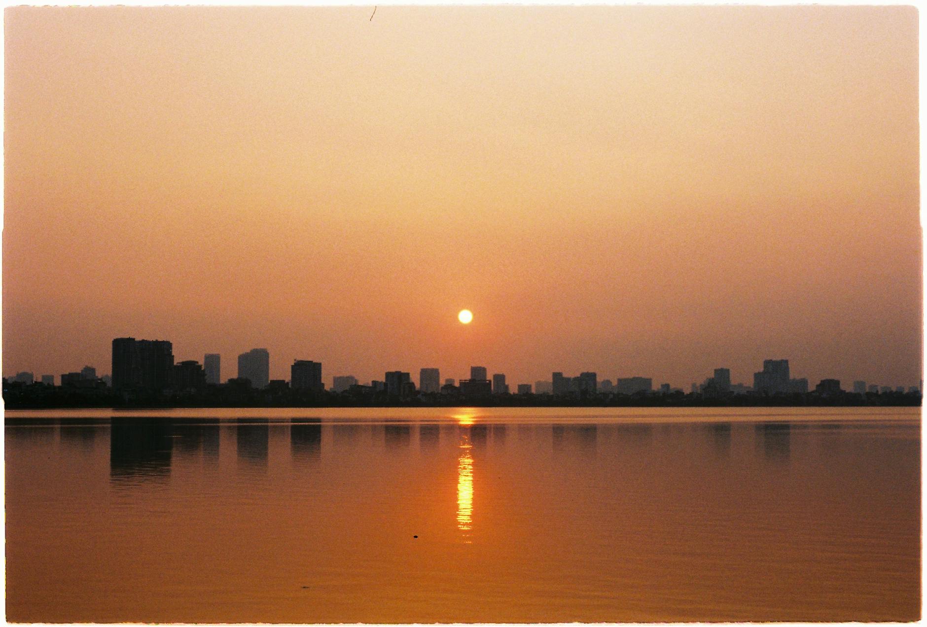 Serene sunset over Hanoi's West Lake with city skyline reflections