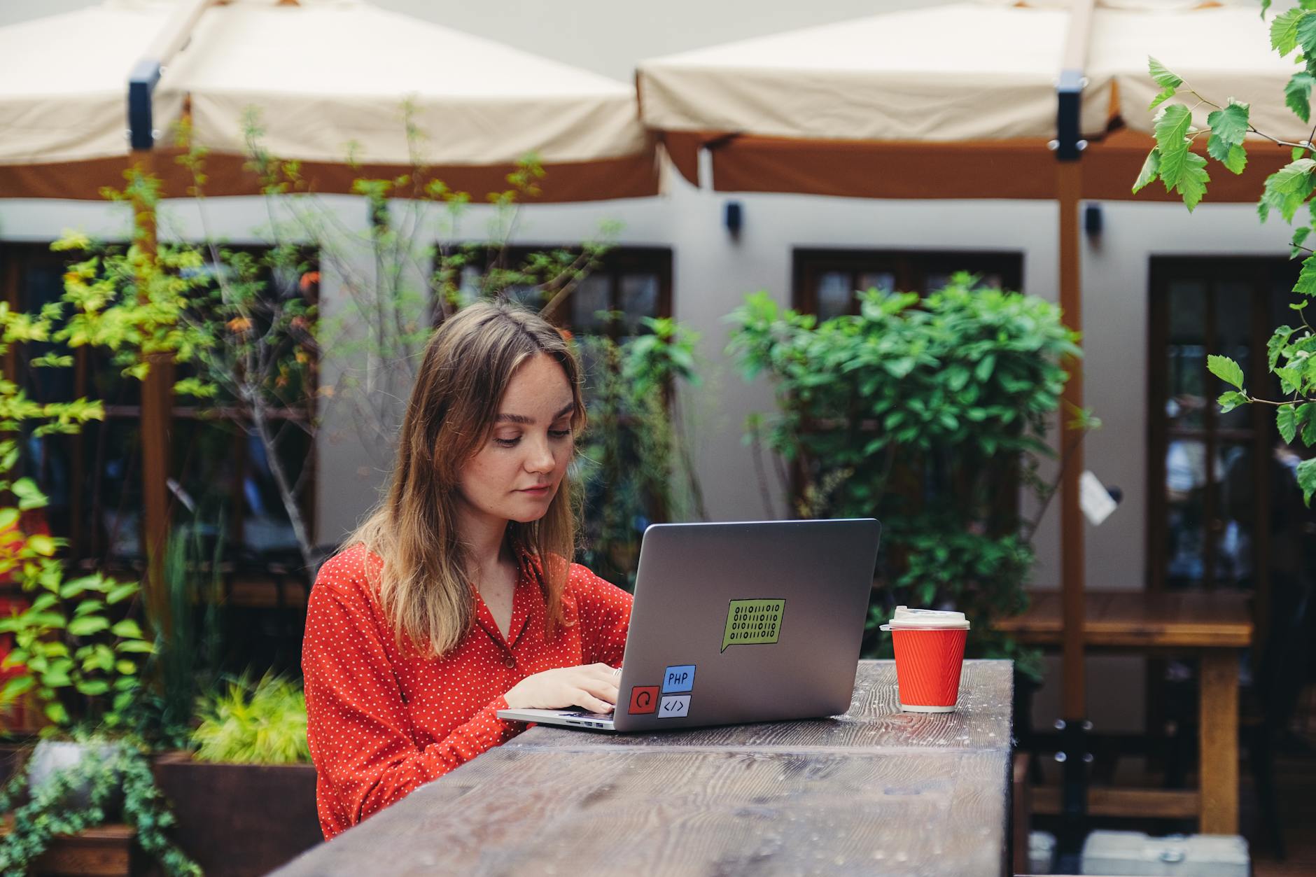 Hanoi Digital Nomad Guide 2026: Visas, Coworking, Wi-Fi & Costs 2 Young woman working on a laptop in an outdoor cafe setting