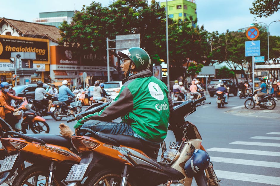 Grab Taxi Hanoi Guide: Booking, Costs & Tips (2026) 3 Motorbike rider in green jacket at busy intersection