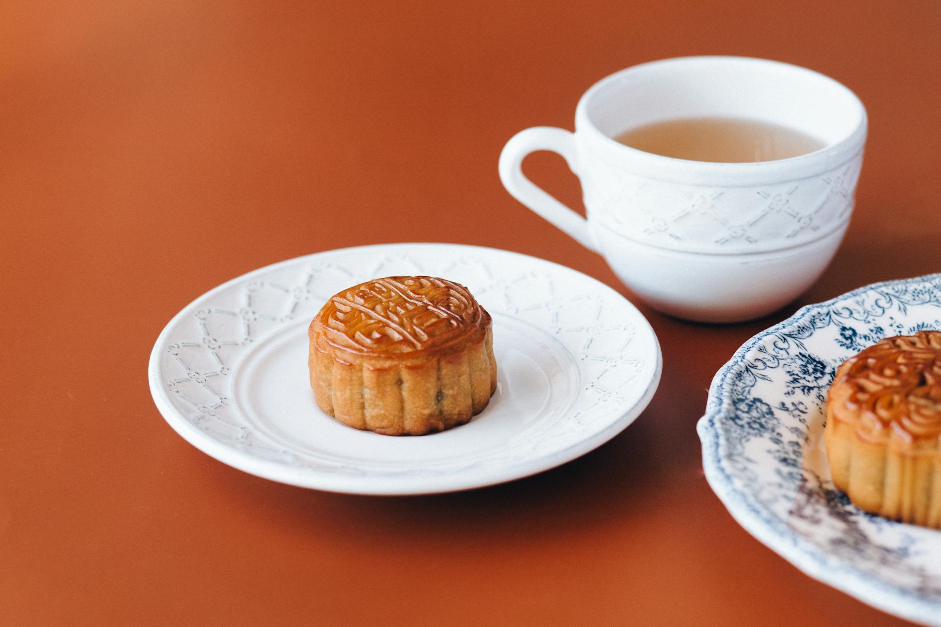 Hanoi Desserts & Sweets: 20 Best Treats & Cafes (2026) 3 Traditional mooncakes served on white plates with a cup of tea
