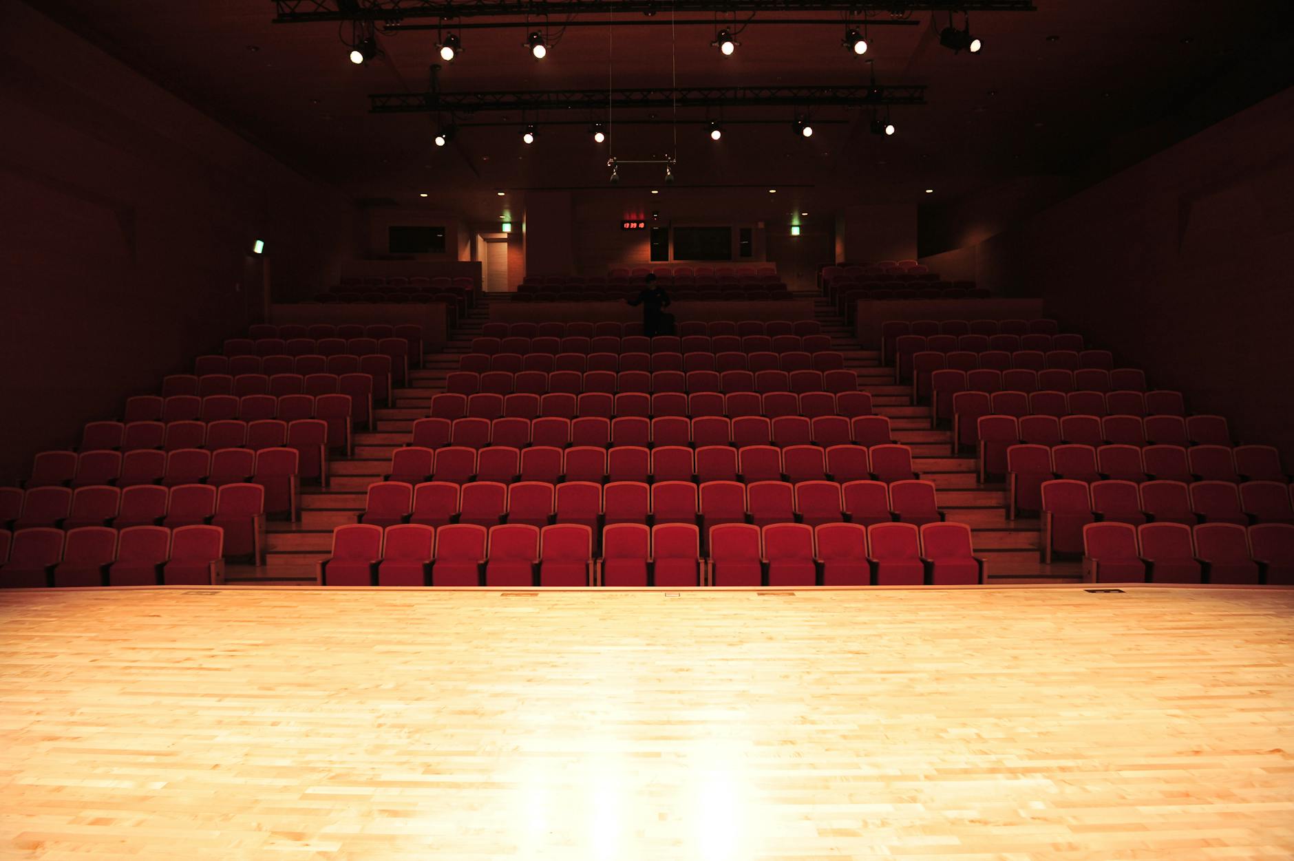 Empty theater interior with rows of red seats and an illuminated stage